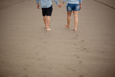 Low section of man walking on sand at beach