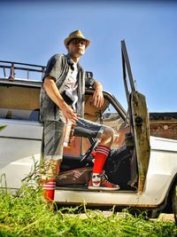 Man standing by car against sky