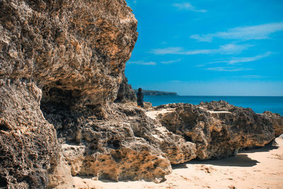 Rock formation on beach against sky