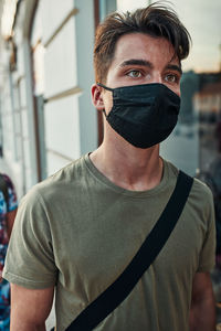 Close-up of young man wearing mask standing outdoors