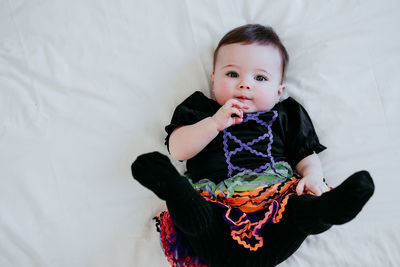 Portrait of cute girl wearing costume lying on bed at home