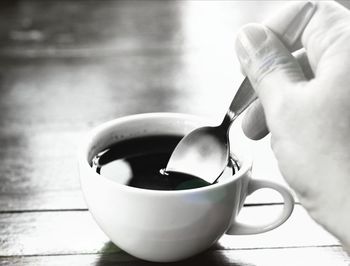 Close-up of hand holding coffee cup on table