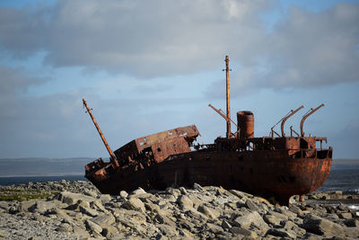 Abandoned ship on beach against sky