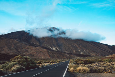 Road leading towards mountains against sky