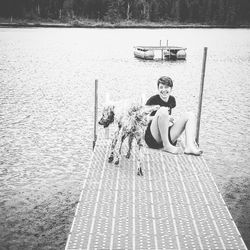 Full length of woman sitting by lake