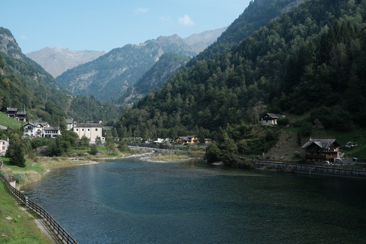 SCENIC VIEW OF RIVER AMIDST BUILDINGS AND MOUNTAINS