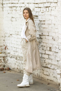 Portrait of young woman standing against brick wall