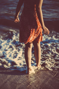 Low section of woman standing on shore at beach