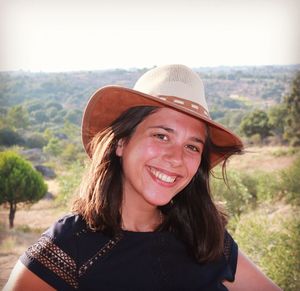 Close-up of cheerful woman wearing hat while standing on landscape