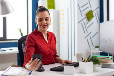 Smiling businesswoman using mobile phone in office