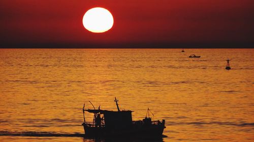 Silhouette boat in sea against sky during sunset