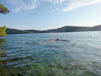 Person swimming in lake against sky