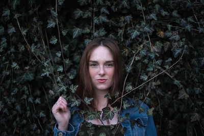 Portrait of young woman with leaves in forest