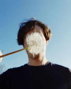 Rear view of man against blue sky with flower