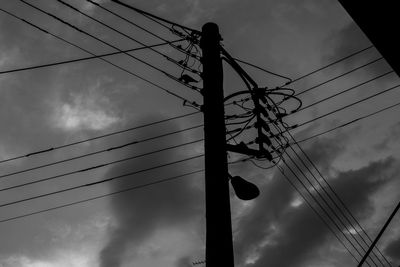 Low angle view of silhouette electricity pylon against sky