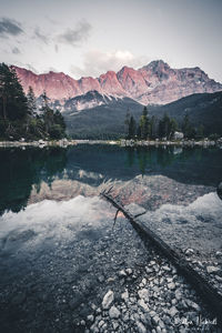 Scenic view of lake by snowcapped mountains against sky