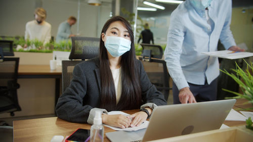 Portrait of businesswoman wearing mask working at office