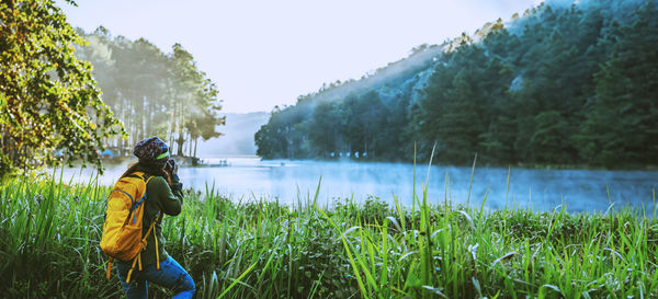 Rear view of woman standing by lake