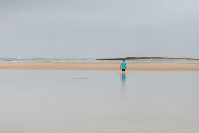 Rear view of man at beach against sky