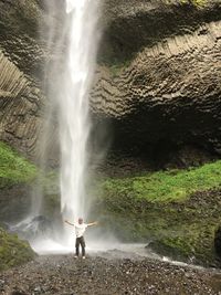 Full length on man standing on rock against waterfall