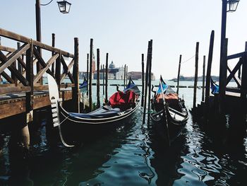 Gondola boats moored by pier in river