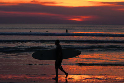 Silhouette man on beach against sky during sunset