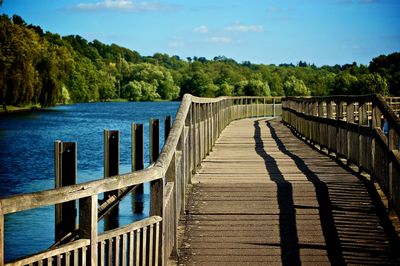 Wooden bridge over river against sky