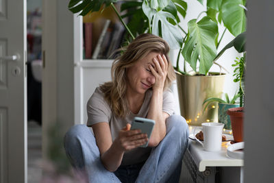 Shy woman using mobile phone at home