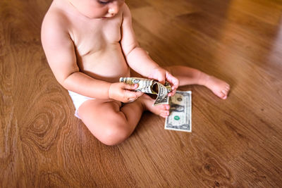 Low section of woman holding paper while sitting on floor