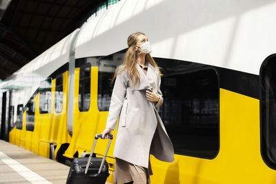 Woman standing by train at railroad station