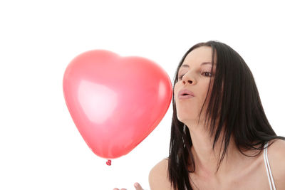 Portrait of young woman with balloons against white background