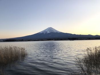 Scenic view of lake by snowcapped mountains against clear sky