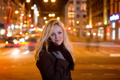 Portrait of young woman standing on city street at night