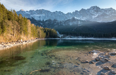 Scenic view of lake by snowcapped mountains against sky