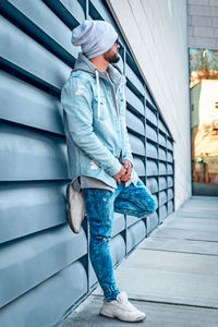 Full length of young man standing against wall