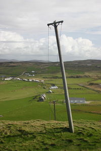 Windmill on grassy field against sky