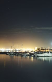 Sailboats moored at harbor against sky at night