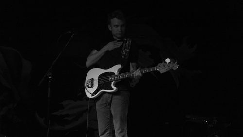 Full length of man holding guitar at night