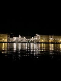 Illuminated buildings by river at night