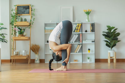 Full length of woman sitting on hardwood floor at home