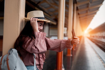 Portrait of young woman wearing hat sitting on seat