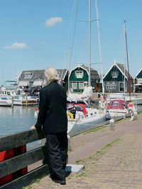 Rear view full length of senior man standing by boats on lake