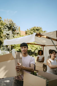 Portrait of smiling male colleague holding cardboard box during charity drive at community center