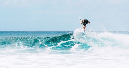 Man surfing on sea against clear sky