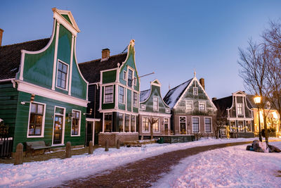 Houses by street against sky during winter