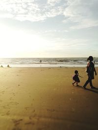 People walking on beach against sky