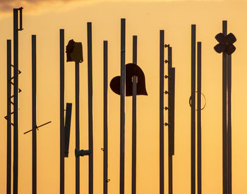 Silhouette sign on pole against sky during sunset