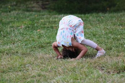 High angle view of girl doing somersault on grass at park