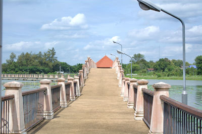 Empty walkway by lake against sky