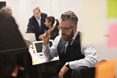 Thoughtful mature businessman planning with colleagues in meeting at office